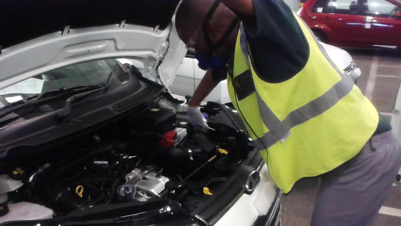 A fitter applying microdots to an engine in a vehicle with the bonnet open